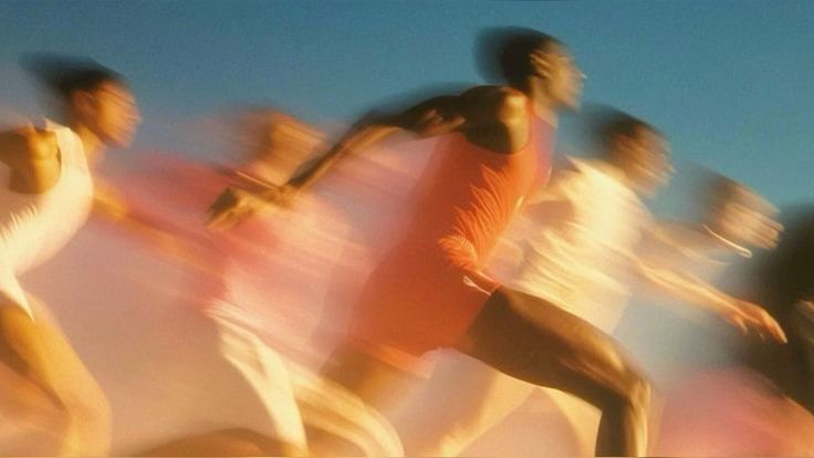 Runners in motion in warm sunlight against a blue sky